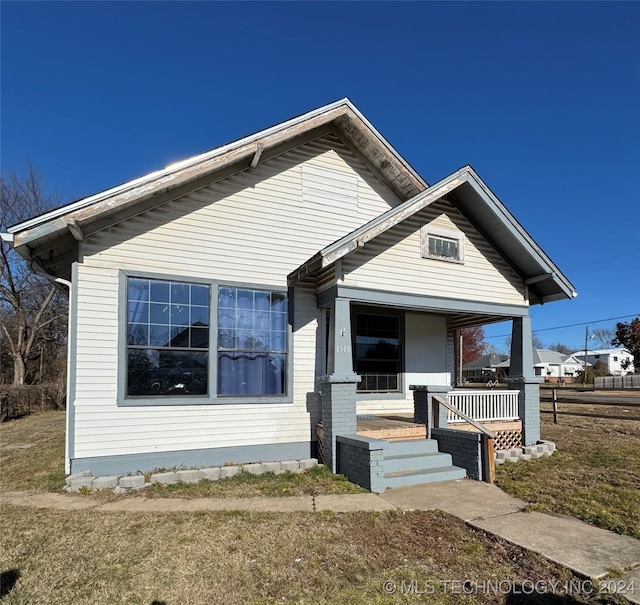 bungalow with a porch and a front lawn