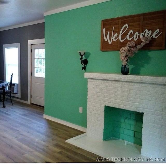 unfurnished living room featuring ornamental molding, hardwood / wood-style floors, and a brick fireplace