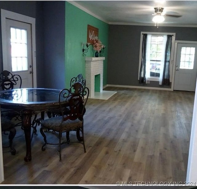 dining area featuring ceiling fan, crown molding, a fireplace, and hardwood / wood-style flooring