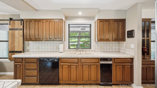 kitchen featuring tasteful backsplash, tile countertops, sink, and black dishwasher