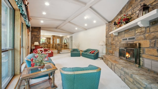 carpeted living room featuring vaulted ceiling with beams and a stone fireplace