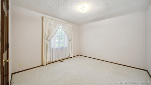 carpeted empty room featuring a textured ceiling