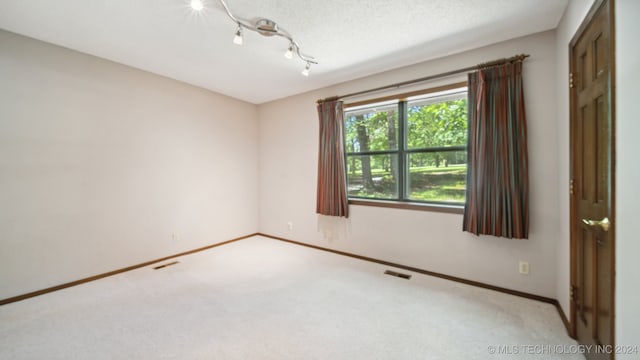 carpeted empty room featuring a textured ceiling