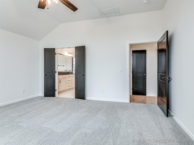 unfurnished bedroom featuring connected bathroom, light colored carpet, vaulted ceiling, and ceiling fan