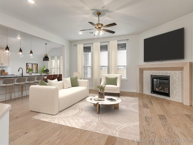 living room with ceiling fan, light wood-type flooring, and a fireplace