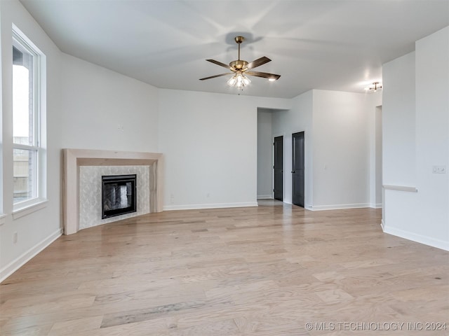 unfurnished living room featuring light hardwood / wood-style floors, ceiling fan, and a premium fireplace