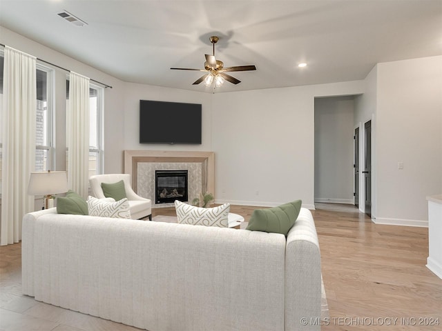 living room with ceiling fan, light hardwood / wood-style floors, and a high end fireplace