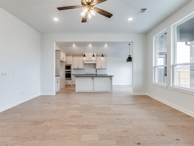 kitchen featuring light hardwood / wood-style flooring, ceiling fan, appliances with stainless steel finishes, decorative light fixtures, and white cabinetry