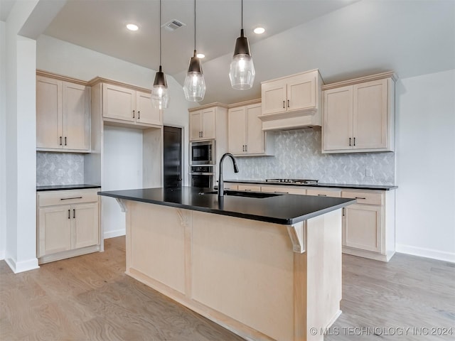 kitchen with backsplash, a center island with sink, hanging light fixtures, light hardwood / wood-style flooring, and stainless steel appliances