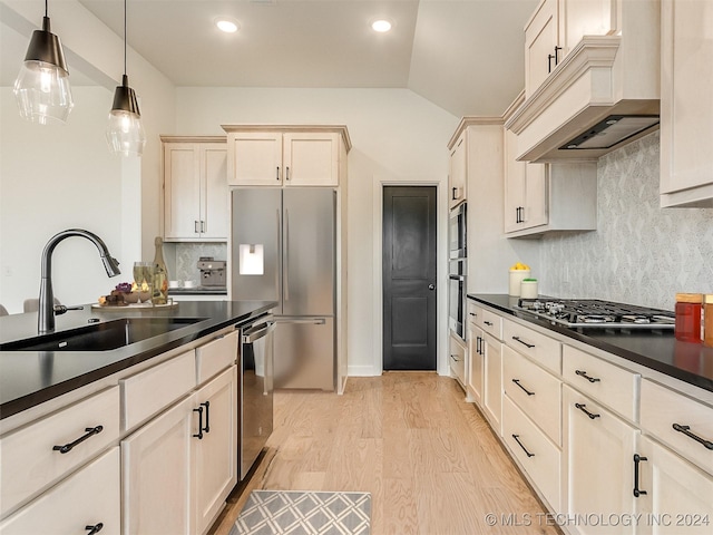 kitchen with lofted ceiling, backsplash, sink, appliances with stainless steel finishes, and decorative light fixtures