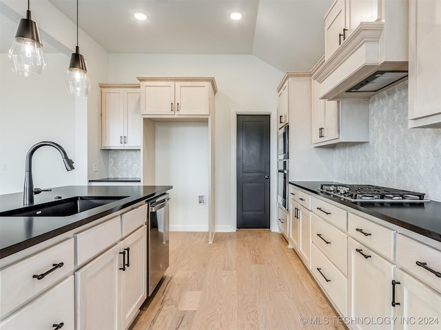 kitchen with tasteful backsplash, custom exhaust hood, sink, decorative light fixtures, and lofted ceiling