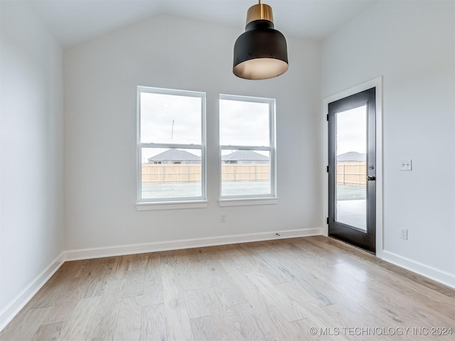 spare room with plenty of natural light, vaulted ceiling, and light hardwood / wood-style flooring