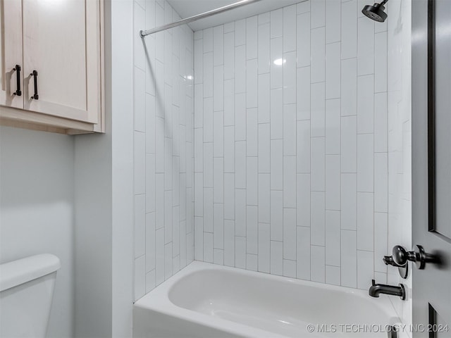 bathroom featuring tiled shower / bath combo and toilet