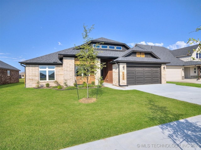 prairie-style home featuring a garage and a front lawn