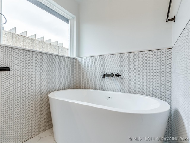 bathroom with tile patterned floors, sink, a bathing tub, and tile walls