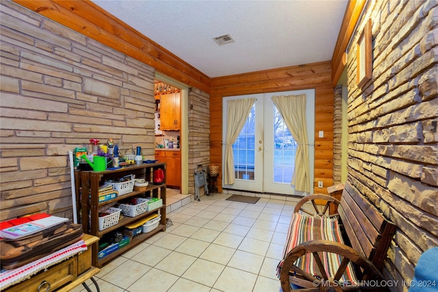 doorway with french doors, a textured ceiling, wood walls, and light tile patterned flooring