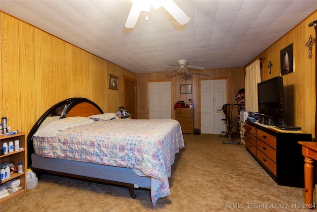 bedroom with light carpet, ceiling fan, and wooden walls