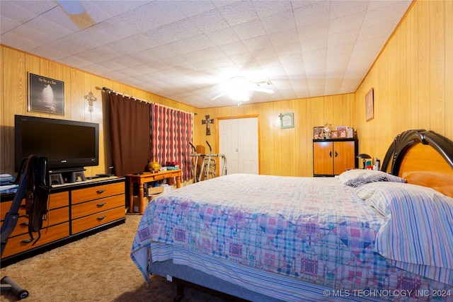 carpeted bedroom with wooden walls and a closet