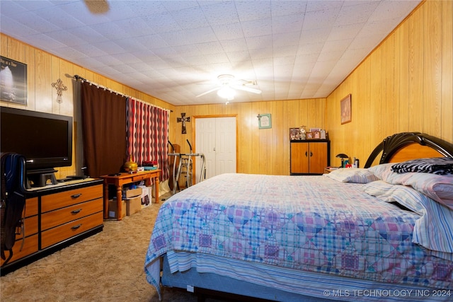 bedroom with ceiling fan, light carpet, wooden walls, and a closet