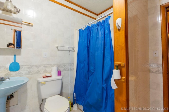 bathroom featuring curtained shower, sink, crown molding, toilet, and tile walls