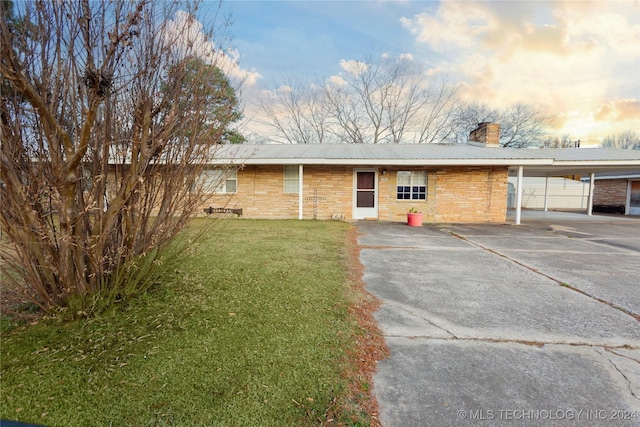 single story home featuring a carport and a lawn