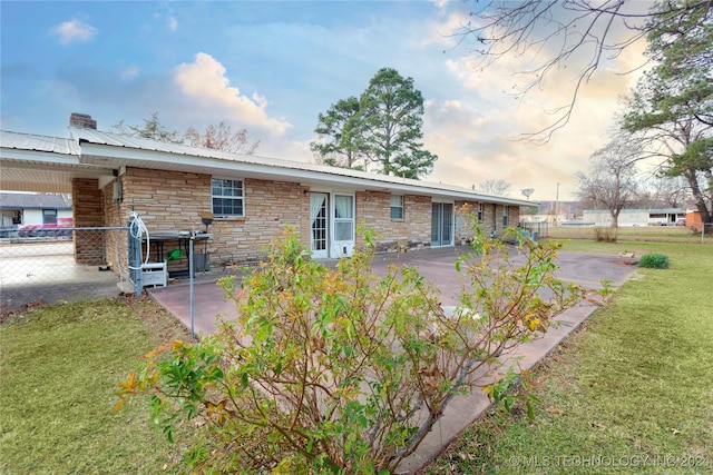 back house at dusk featuring a patio area and a yard