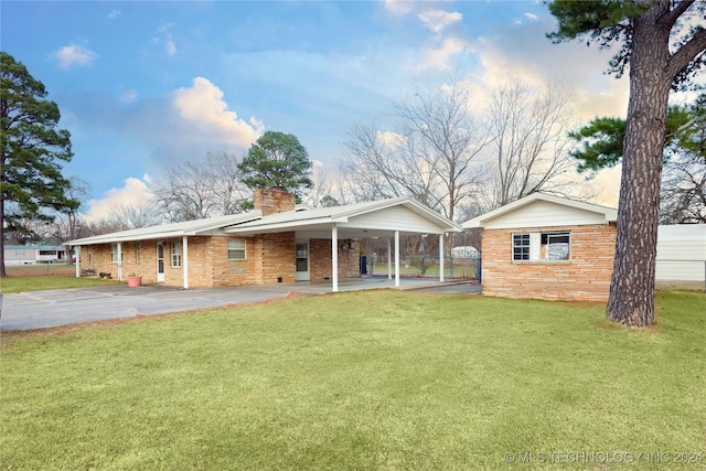 back house at dusk with a lawn and a carport