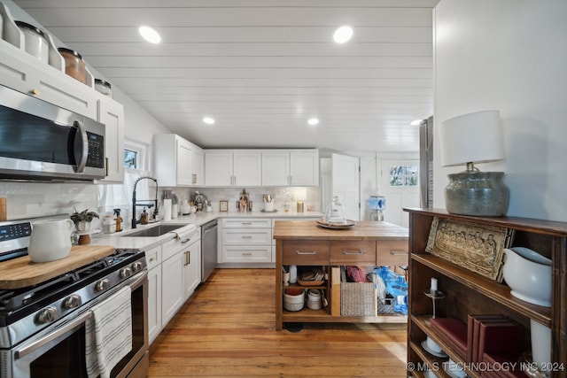 kitchen featuring white cabinets, sink, light hardwood / wood-style flooring, decorative backsplash, and stainless steel appliances