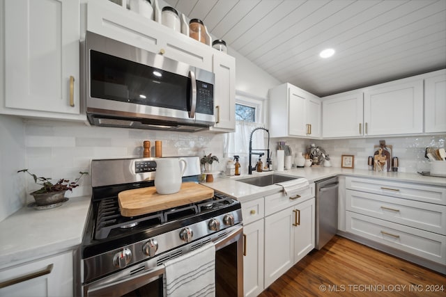 kitchen with decorative backsplash, white cabinetry, sink, and appliances with stainless steel finishes