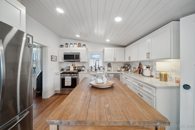 kitchen with lofted ceiling, white cabinets, sink, wood-type flooring, and stainless steel appliances