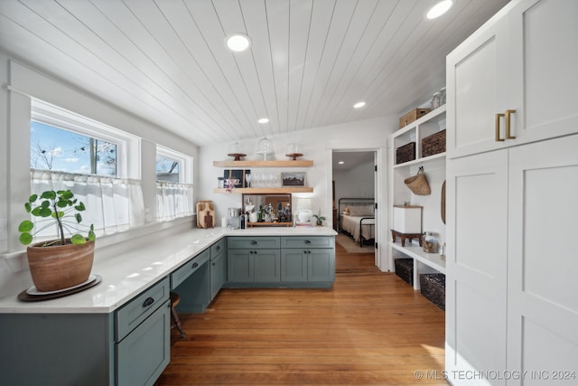 kitchen with wood ceiling, kitchen peninsula, light hardwood / wood-style floors, and lofted ceiling