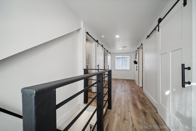 hall with a barn door and wood-type flooring