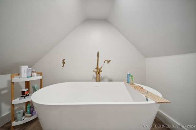 bathroom featuring a tub, wood-type flooring, and vaulted ceiling