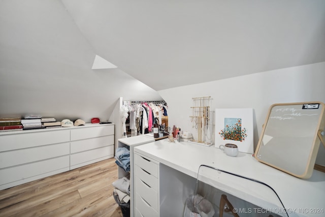 walk in closet featuring light wood-type flooring and vaulted ceiling