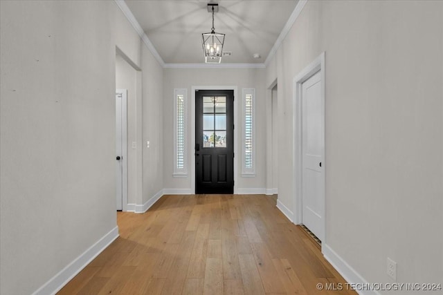 foyer entrance with light wood-type flooring, an inviting chandelier, and crown molding