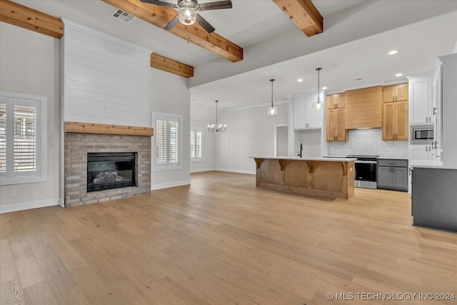 kitchen featuring a center island, hanging light fixtures, stainless steel appliances, light hardwood / wood-style floors, and white cabinets