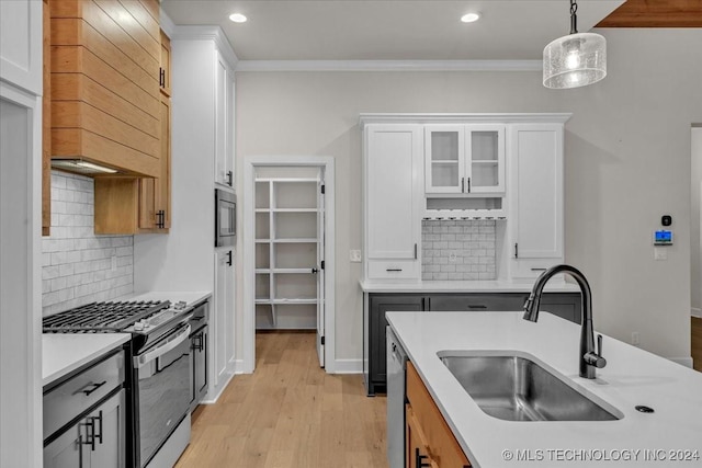 kitchen featuring decorative backsplash, appliances with stainless steel finishes, decorative light fixtures, light hardwood / wood-style floors, and white cabinetry