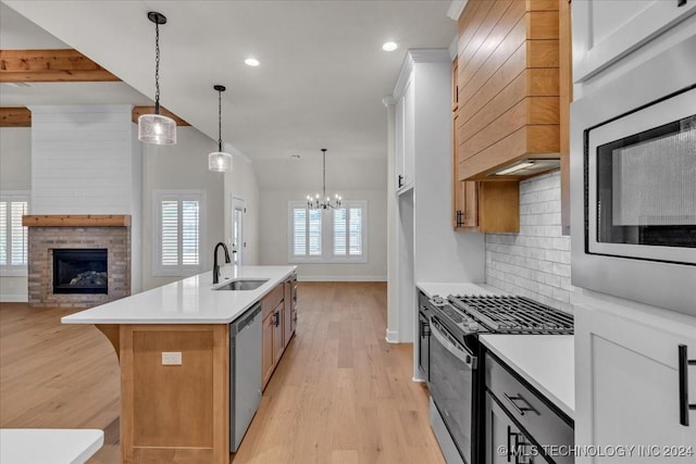 kitchen with a healthy amount of sunlight, a center island with sink, stainless steel appliances, and light wood-type flooring