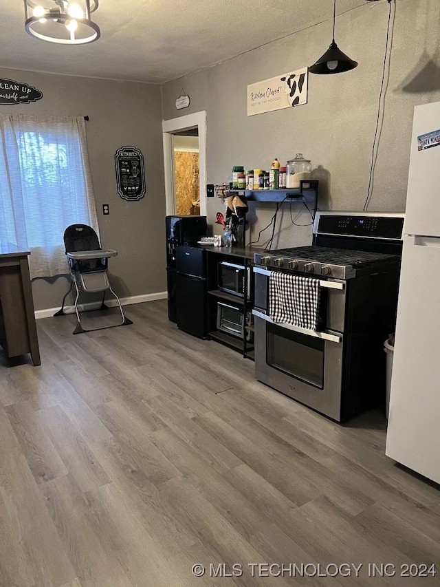 kitchen with hardwood / wood-style floors, range with two ovens, a textured ceiling, decorative light fixtures, and white fridge