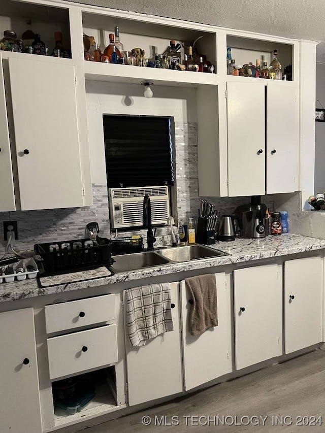 kitchen with backsplash, light hardwood / wood-style flooring, white cabinets, and sink