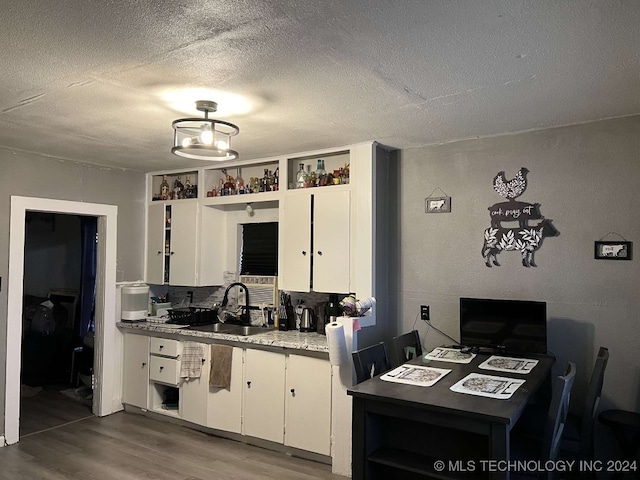 kitchen featuring white cabinetry, sink, a textured ceiling, and hardwood / wood-style flooring