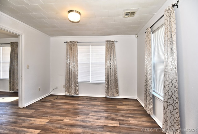 spare room featuring crown molding and dark wood-type flooring