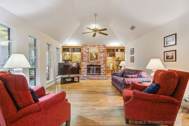 living room featuring built in shelves, ceiling fan, plenty of natural light, and light hardwood / wood-style flooring