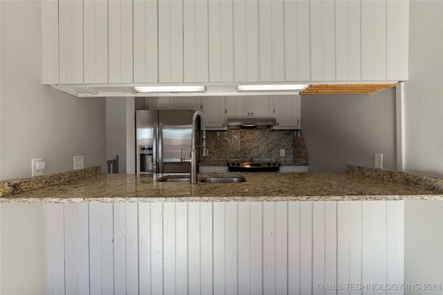 kitchen featuring kitchen peninsula, decorative backsplash, appliances with stainless steel finishes, and sink