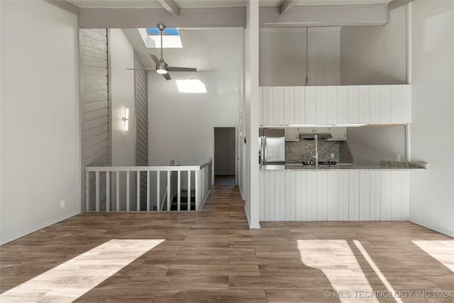 kitchen featuring a skylight, wood-type flooring, beam ceiling, white cabinets, and stainless steel fridge with ice dispenser