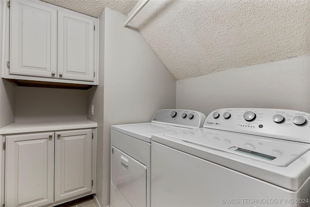 laundry area featuring cabinets, a textured ceiling, and washing machine and clothes dryer