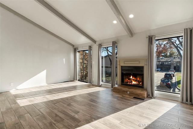 unfurnished living room with vaulted ceiling with beams and light wood-type flooring