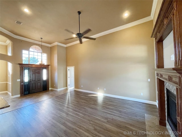 entryway with ceiling fan, a towering ceiling, dark wood-type flooring, and ornamental molding