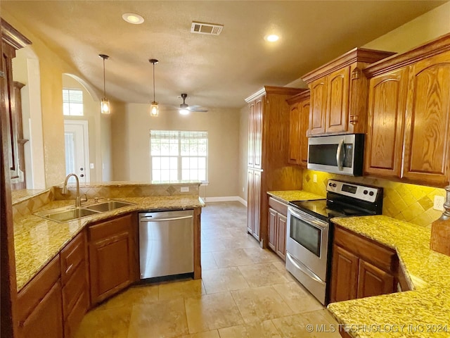 kitchen with a healthy amount of sunlight, sink, stainless steel appliances, and hanging light fixtures