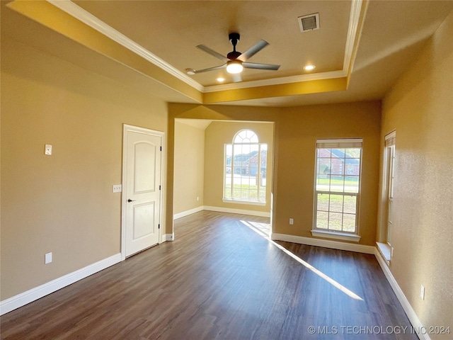 empty room featuring a raised ceiling, ceiling fan, dark hardwood / wood-style flooring, and crown molding